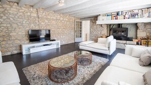 A modern living room with stone walls, a flat-screen TV, white sofas, and a fireplace. - Longère classée 4 étoiles - piscine  – Ambillou (Ambillou)