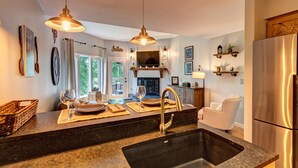 A modern kitchen with granite countertops, stainless steel appliances, pendant lighting, and a fireplace. - Mountain Modern Condo on EagleVail Golf Course near Vail and Beaver Creek (Avon)