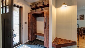 A hallway with a wooden door, a bench, and baskets on shelves. - Mountain Modern Condo on EagleVail Golf Course near Vail and Beaver Creek (Avon)