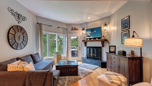 A living room with a fireplace, a clock, and a television. - Mountain Modern Condo on EagleVail Golf Course near Vail and Beaver Creek (Avon)