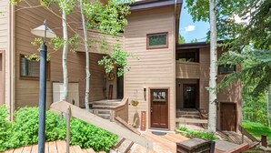 A multi-story building with a wooden exterior, a front door, and a staircase leading to the entrance. - Mountain Modern Condo on EagleVail Golf Course near Vail and Beaver Creek (Avon)