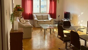 A living room with a sofa, a glass coffee table, a TV, and a dining table with chairs. - Luminosidade, in front of Parque da Luz / 5 minutes from the Metro. (São Paulo)