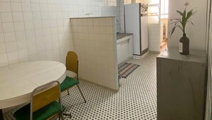 A small, tiled kitchen with a round table and chairs, a refrigerator, and a potted plant. - Luminosidade, in front of Parque da Luz / 5 minutes from the Metro. (São Paulo)