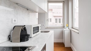 A modern kitchen with a built-in oven, a kettle, and a coffee maker.