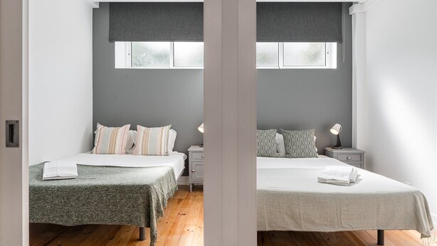 A modern bedroom with two beds, grey walls, and wooden flooring. - GuestReady Economy - Gold Leaf GF (Porto)