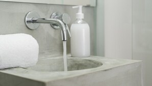 Ein Waschbecken mit fließendem Wasser, ein weißes Handtuch und eine Seifenspender.