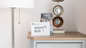 A welcome sign, a city map of Porto, and a decorative metal sculpture on a wooden table. - GuestReady  Economy - Gold Leaf 2B (Porto)