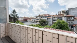 A balcony with tiled flooring and a view of a residential area with buildings and trees. - GuestReady  Economy - Gold Leaf 2B (Porto)