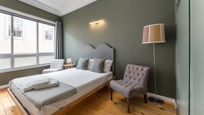 Une chambre avec un grand lit, une table de chevet avec une lampe, une chaise et un lampadaire.