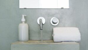 Une salle de bain équipée d’un lavabo, d’un robinet, d’un distributeur de savon et d’une serviette.
