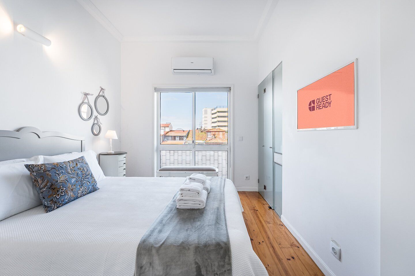 Quarto de hotel moderno com uma cama grande, vista da cidade através de uma varanda e um aviso indicando que o quarto está pronto para hóspedes.