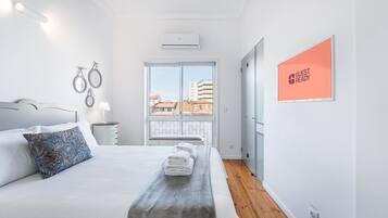 Quarto de hotel moderno com uma cama grande, vista da cidade através de uma varanda e um aviso indicando que o quarto está pronto para hóspedes.