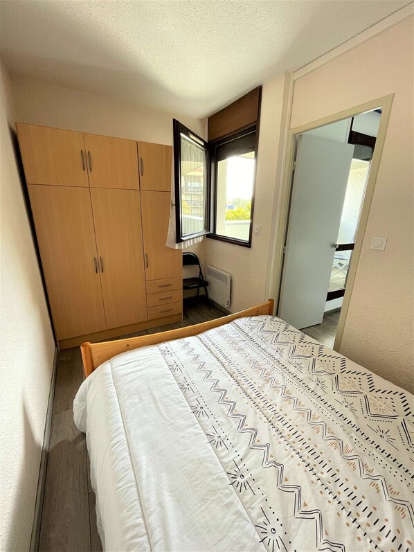 Een slaapkamer met een bed, een kledingkast, een radiator en een raam.
