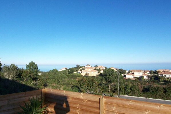 A coastal village with terraced houses, a clear sky, and a wooden fence in the foreground. - APPARTMENT CLEMENT - SEA VIEW (SOLENZARA)