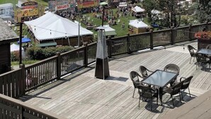 Terraza con asientos al aire libre con vistas a una zona montañosa con telesillas y un festival.