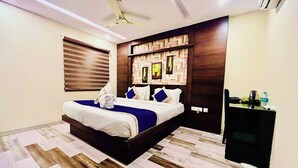 Una habitación de hotel moderna con una cama grande, cabecera de madera y televisor integrado.