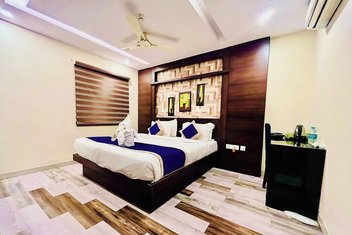 Une chambre d’hôtel moderne avec un grand lit, une tête de lit en bois et un téléviseur intégré.