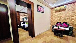 Habitación de hotel con cama, sofá, una mesita con un florero y aire acondicionado instalado en la pared.