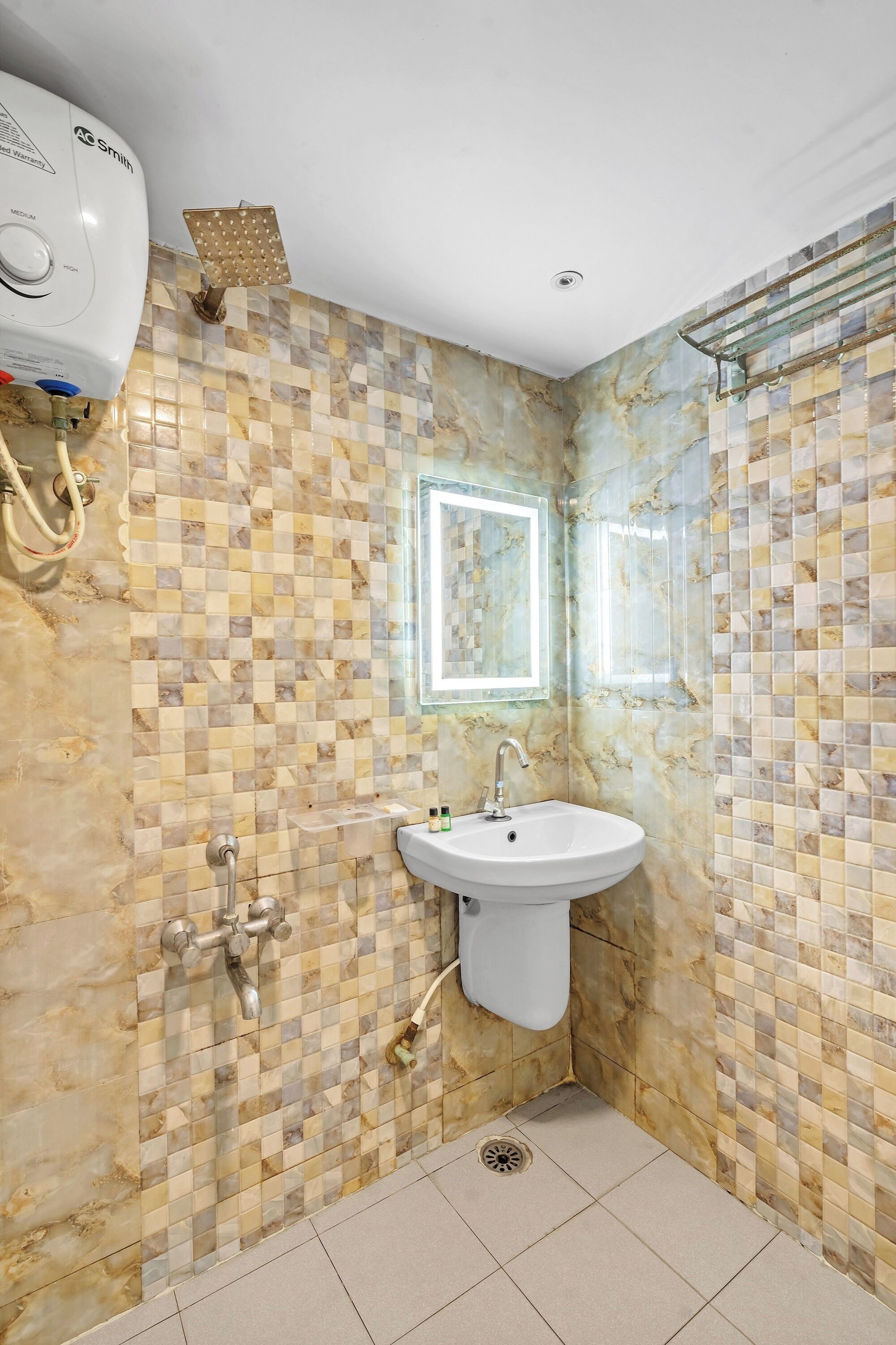 Een badkamer met een wand betegeld met ruitjes, een witte wastafel en een handdouche.