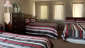 A bedroom with two beds, a dresser, a ceiling fan, and a window with curtains.