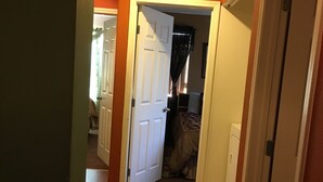 A hallway with wooden flooring, a white door, and a laundry machine in the background.