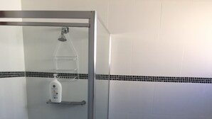 A glass-enclosed shower with a handheld showerhead, a handheld soap dispenser, and a small shelf. - Cute country cottage in Cessnock (Cessnock)