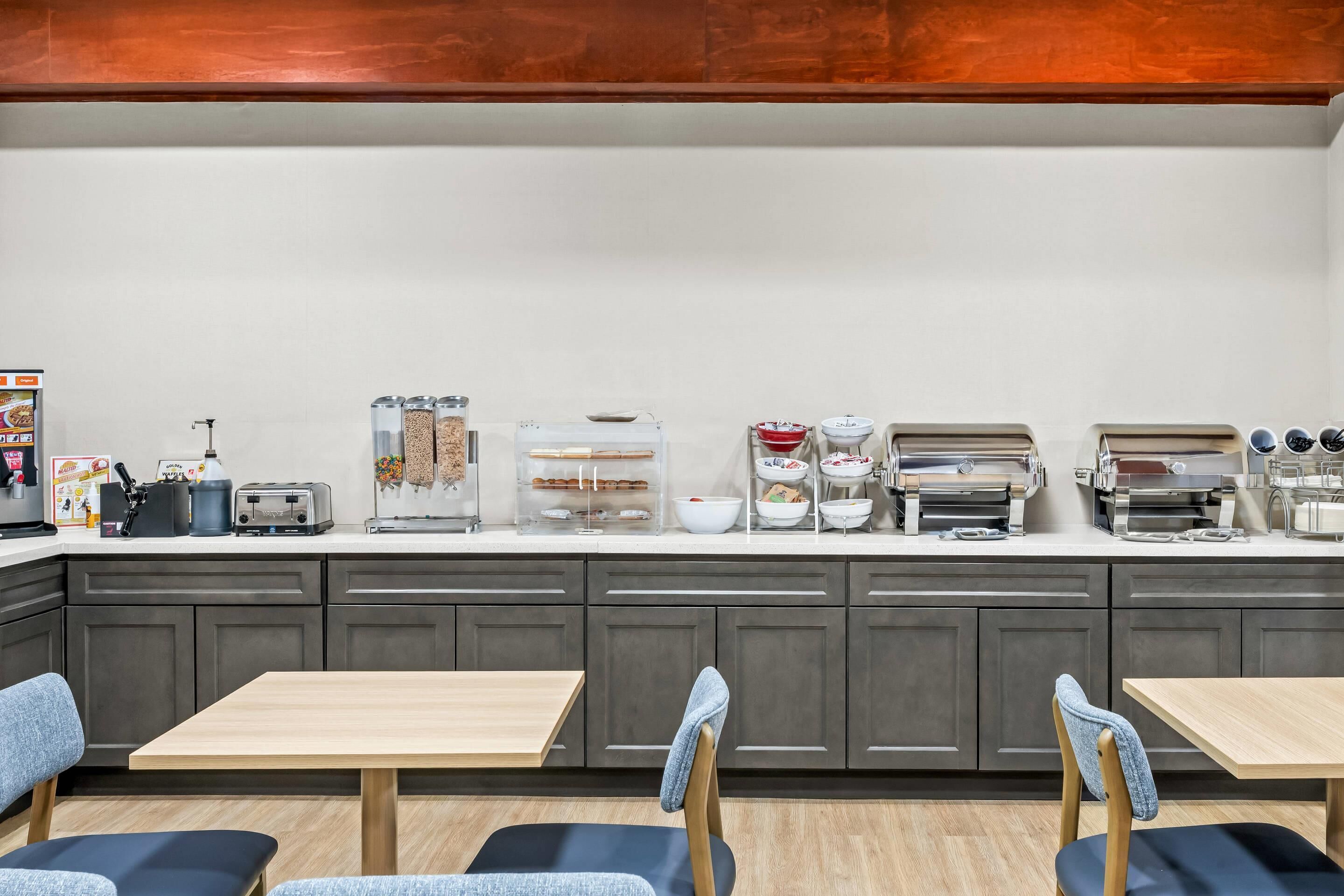 Une cuisine moderne dotée d’un bar-comptoir pour prendre le petit-déjeuner, équipé de divers appareils électroménagers et d’un espace dédié au café.