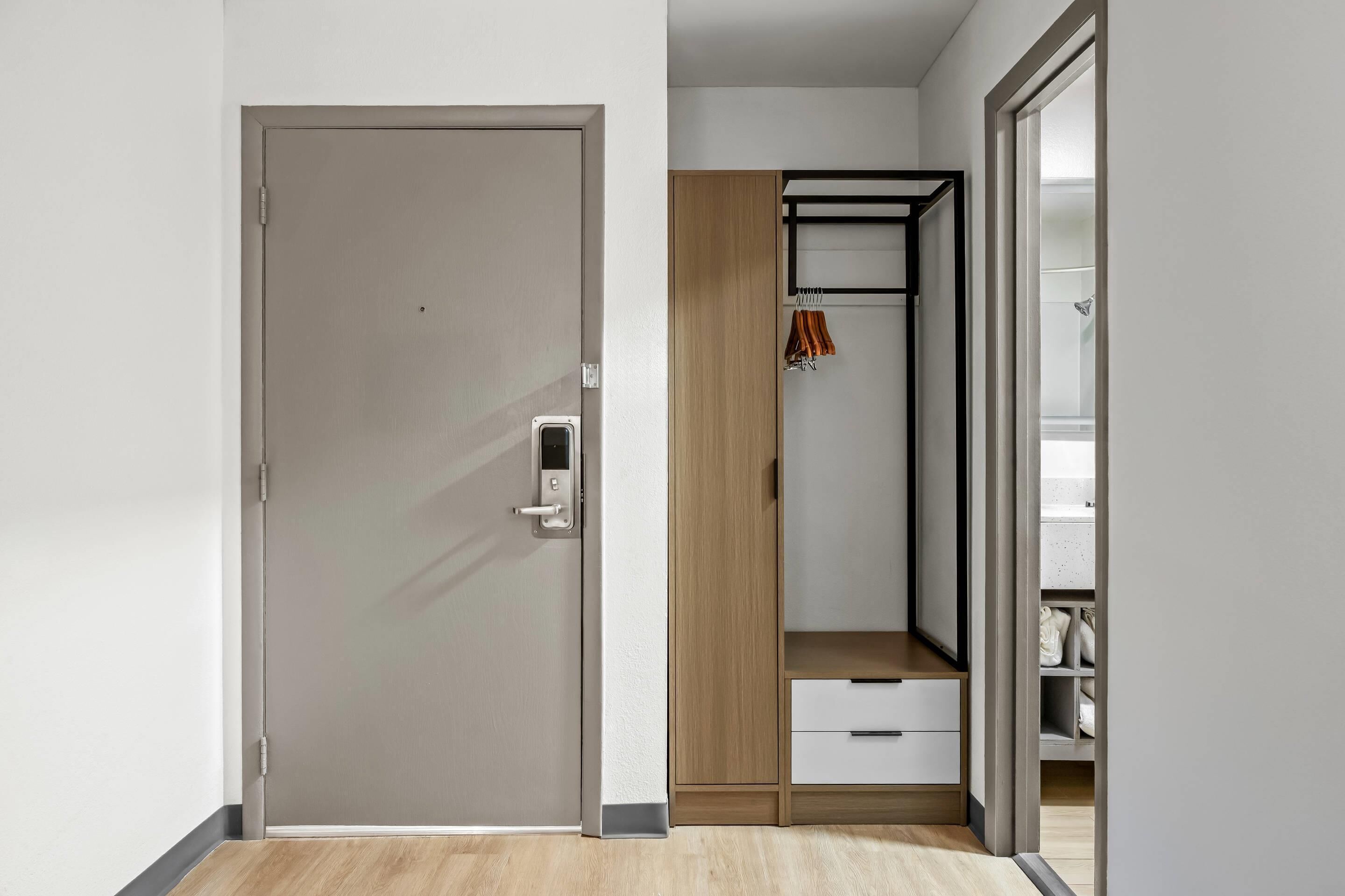 A modern room with a sliding door, a wooden wardrobe, and a built-in bench with a hanging towel.