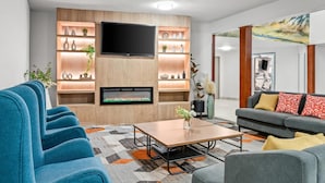 Un salon moderne doté d’un téléviseur à écran plat, d’étagères intégrées, d’une cheminée et d’un canapé agrémenté de coussins décoratifs.