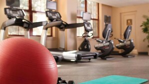 Een sportschool met trainingsapparatuur, een rode fitnessbal en een groene mat.