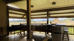 An outdoor covered patio with a grill, bar stools, and a refrigerator.