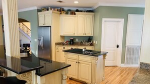 A kitchen with cream-colored cabinetry, a black countertop, and a stainless steel refrigerator.