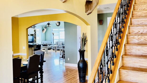 A staircase with a wooden handrail and black balusters, leading to a second floor. Deer antlers are mounted on the walls above the staircase.