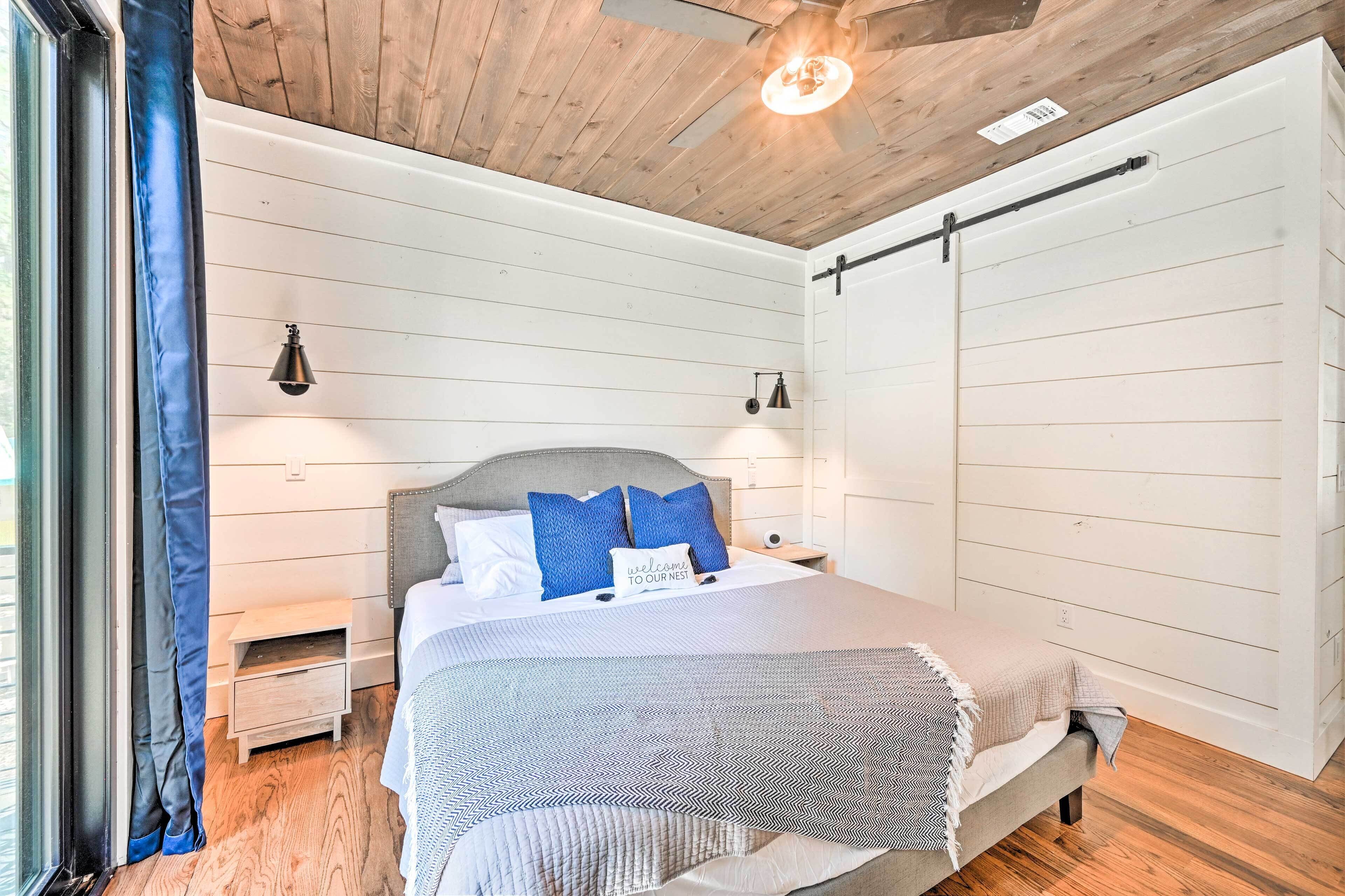 A bedroom with a bed, bedside tables, a nightstand, a ceiling fan, and a sliding door.