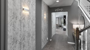 Un hall d’entrée moderne avec des murs en marbre, un escalier en bois et une pancarte « Bienvenue ».