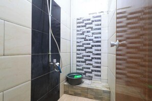 Une salle de bain comprenant un espace douche, des toilettes et un lavabo.