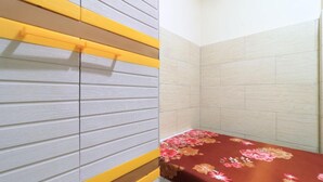 Une pièce avec un lit, un mur à rayures jaunes et grises et une zone de douche carrelée.
