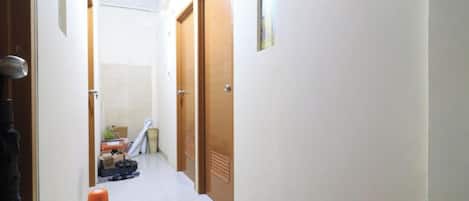 A narrow hallway with white tiled floors and wooden doors.