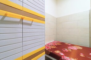 Una habitación con una cama, un pared a rayas amarillo y gris, y una zona de ducha con azulejos.