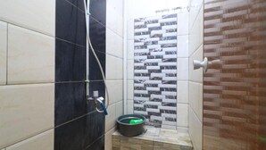 Une salle de bain avec des murs carrelés, un espace douche et des toilettes.