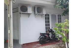 Un edificio con dos unidades de aire acondicionado en la pared exterior, una motocicleta estacionada frente a él y una puerta que da al acceso.