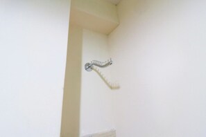 Un coin de pièce avec un mur blanc et un porte-serviettes en métal.