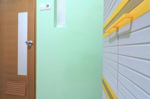 Une porte ornée d’une bande verticale blanche, un mur vert clair et un mur blanc texturé avec des touches de jaune.