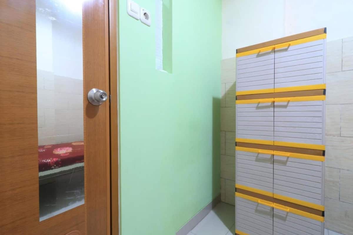 Una habitación con una puerta de madera, una pared verde claro y un armario con pomos amarillos.