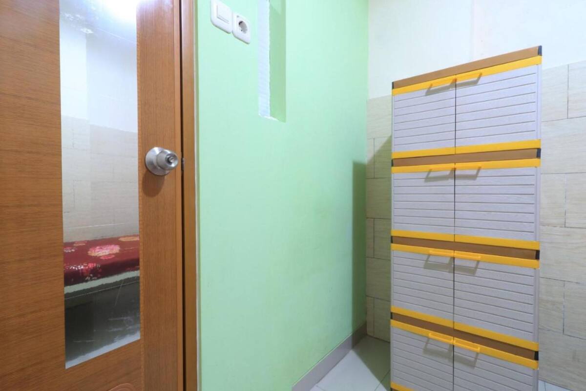 A room with a wooden door, a light green wall, and a storage unit with yellow handles.
