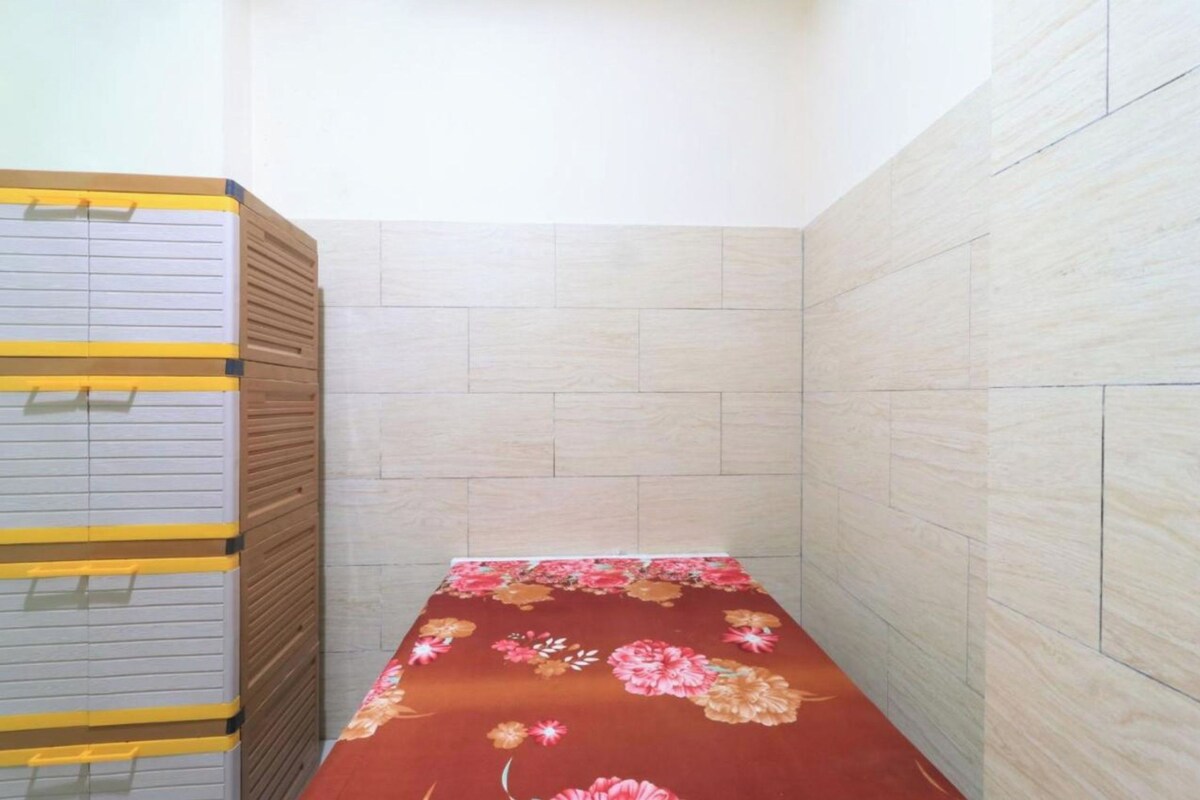 Una habitación pequeña con cama, un armario de madera y paredes de baldosas.