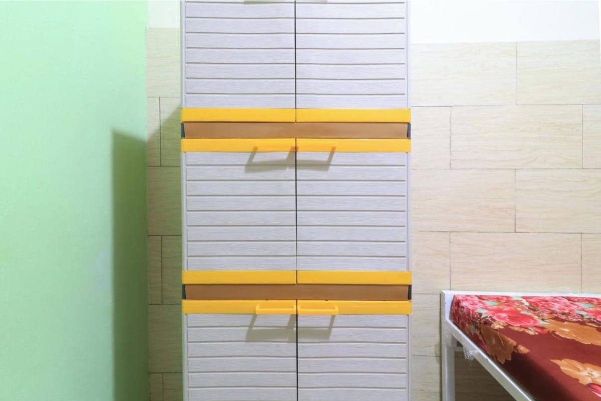 Una habitación con un armario gris con detalles amarillos y una cama con colcha estampada.