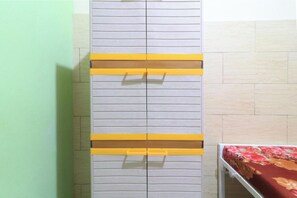 Una habitación con un armario gris con detalles amarillos y una cama con colcha estampada.