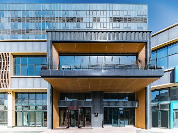 A modern building with a glass facade, a central entrance with a ramp, and a visible logo on the entrance. - Yaduo Hotel Beijing Zhongguancun Life Science Park (Beijing)