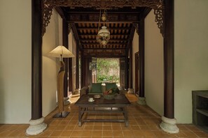 A corridor with a wooden ceiling, a table with a bowl and a cup, and a hanging lamp. - Anhill Boutique (Hue)